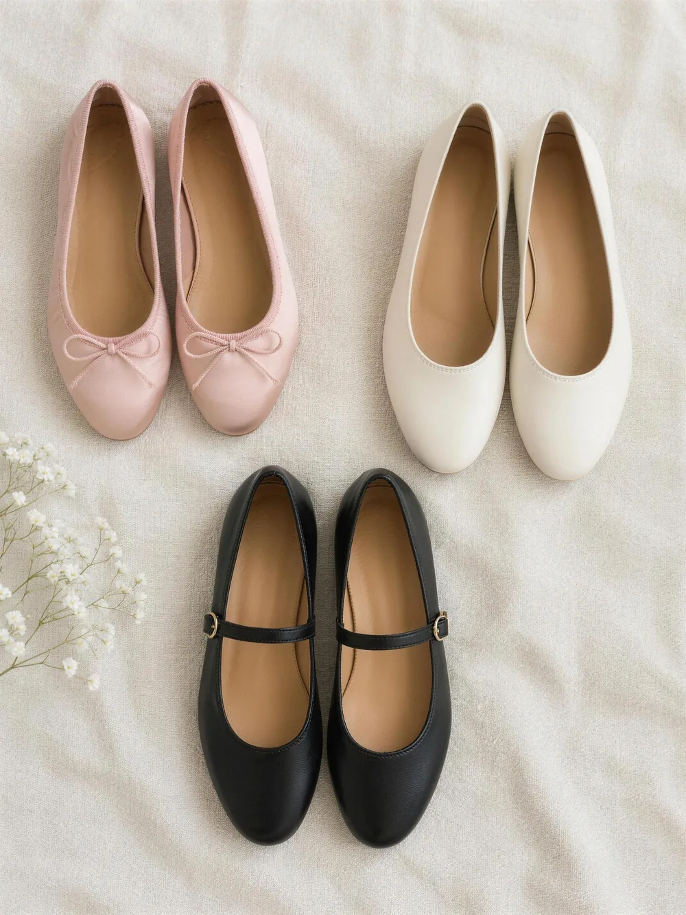 Three pairs of ballet flats on cream linen: blush satin with a bow, ivory leather and black leather mary janes