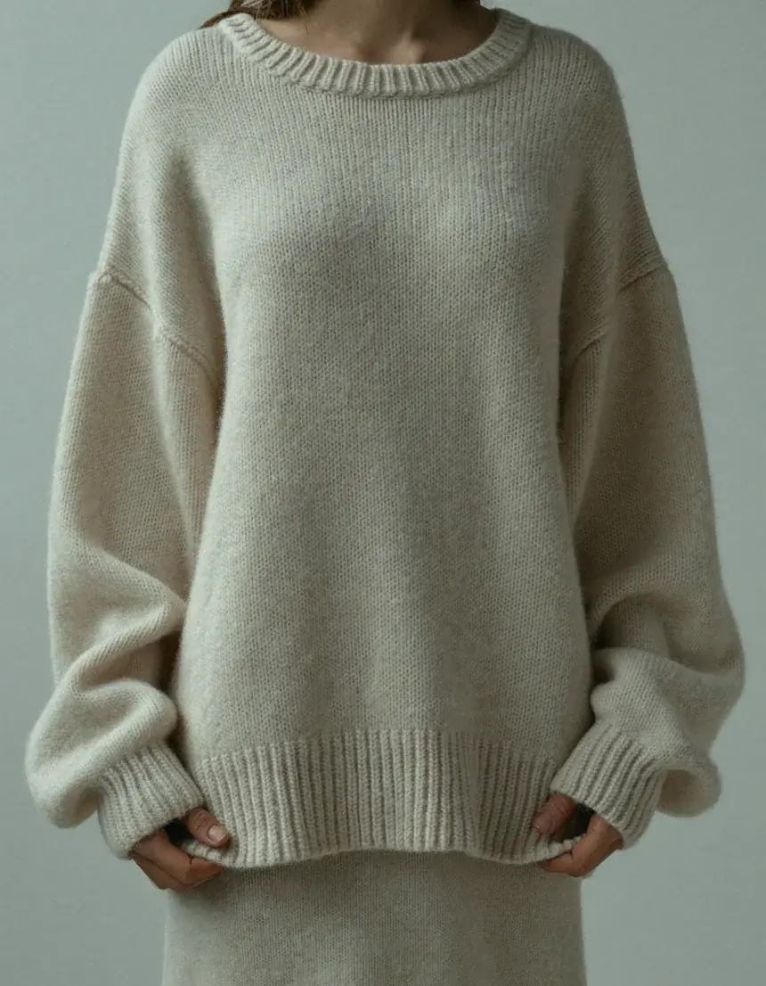 A woman wearing an oversized cream cashmere jumper, shown from the chest down