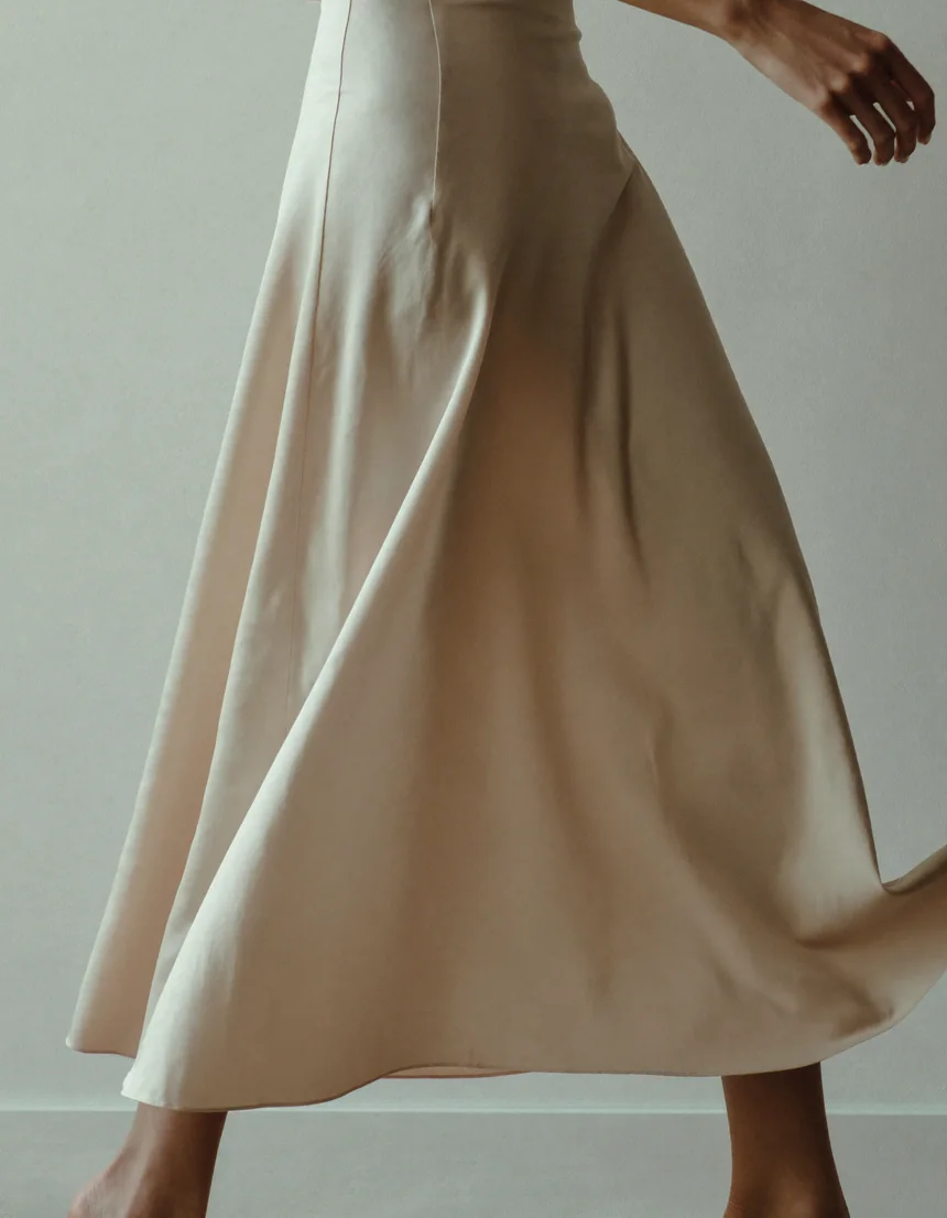 A woman mid-stride in a flowing pale champagne satin midi skirt