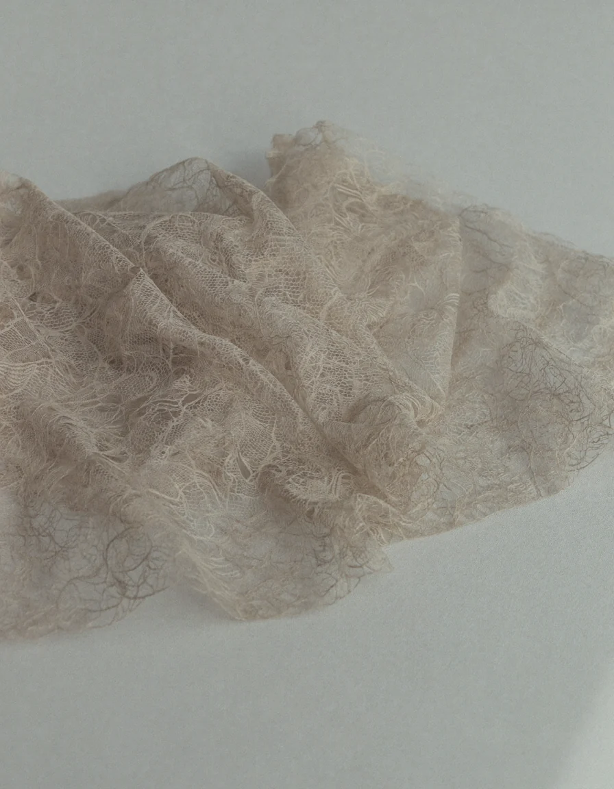 A close study of fine pale nude lace fabric lying in soft gentle folds