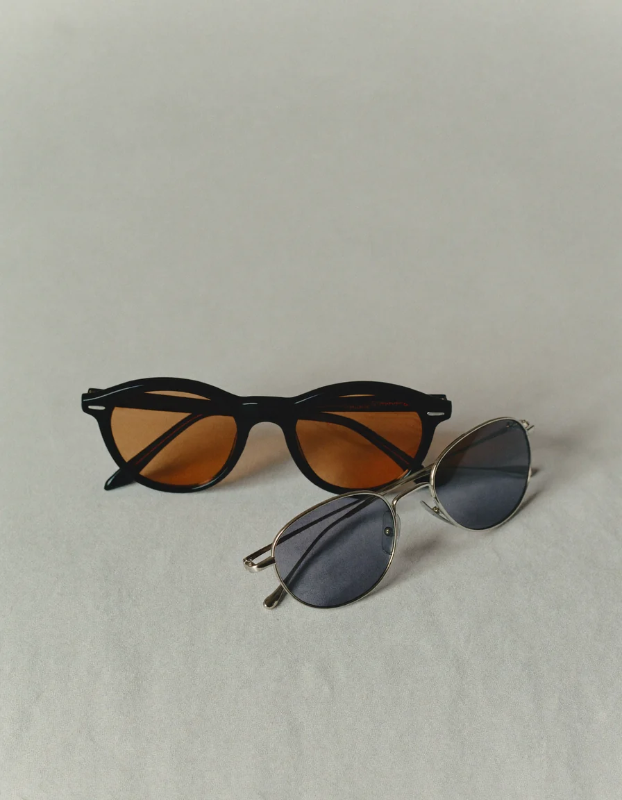 Two pairs of sunglasses, one with warm amber lenses and one with cool grey lenses