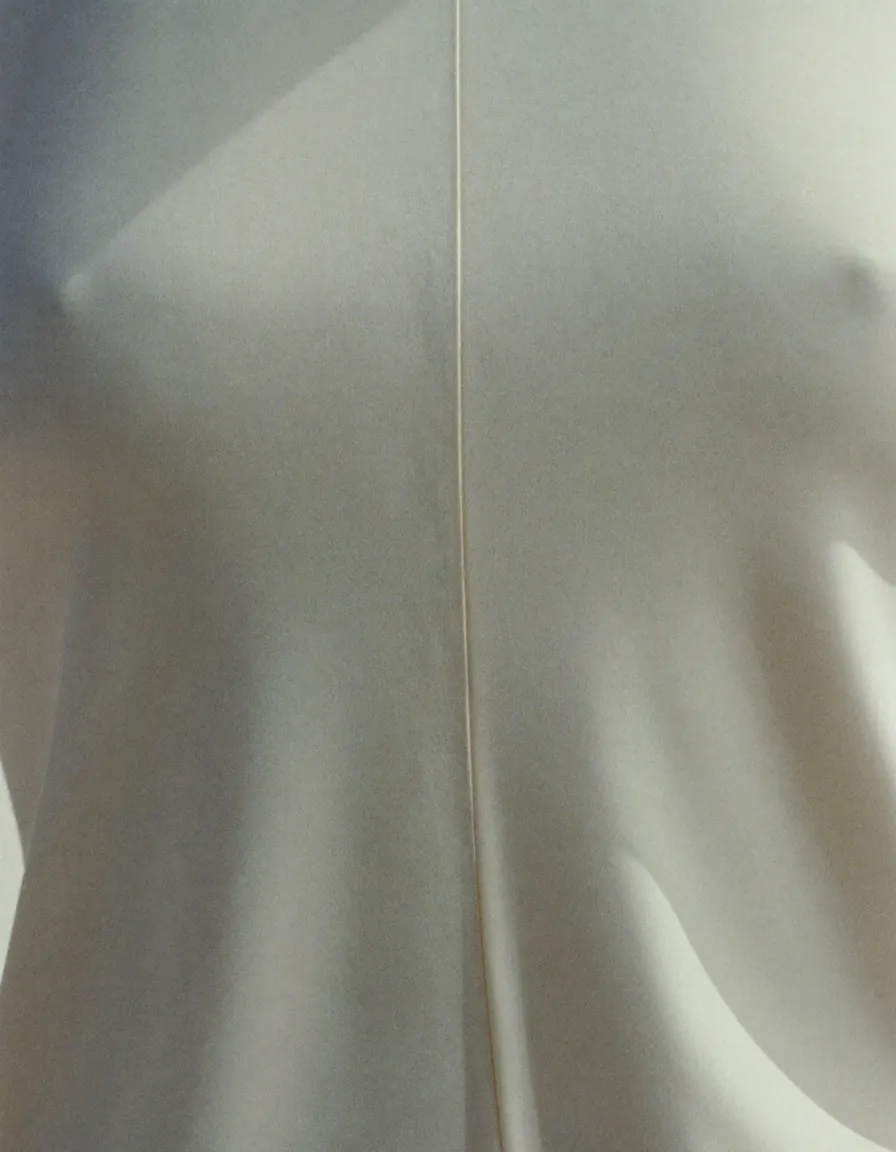 Smooth ivory stretch jersey in soft folds, with one flat-bonded seam running through it
