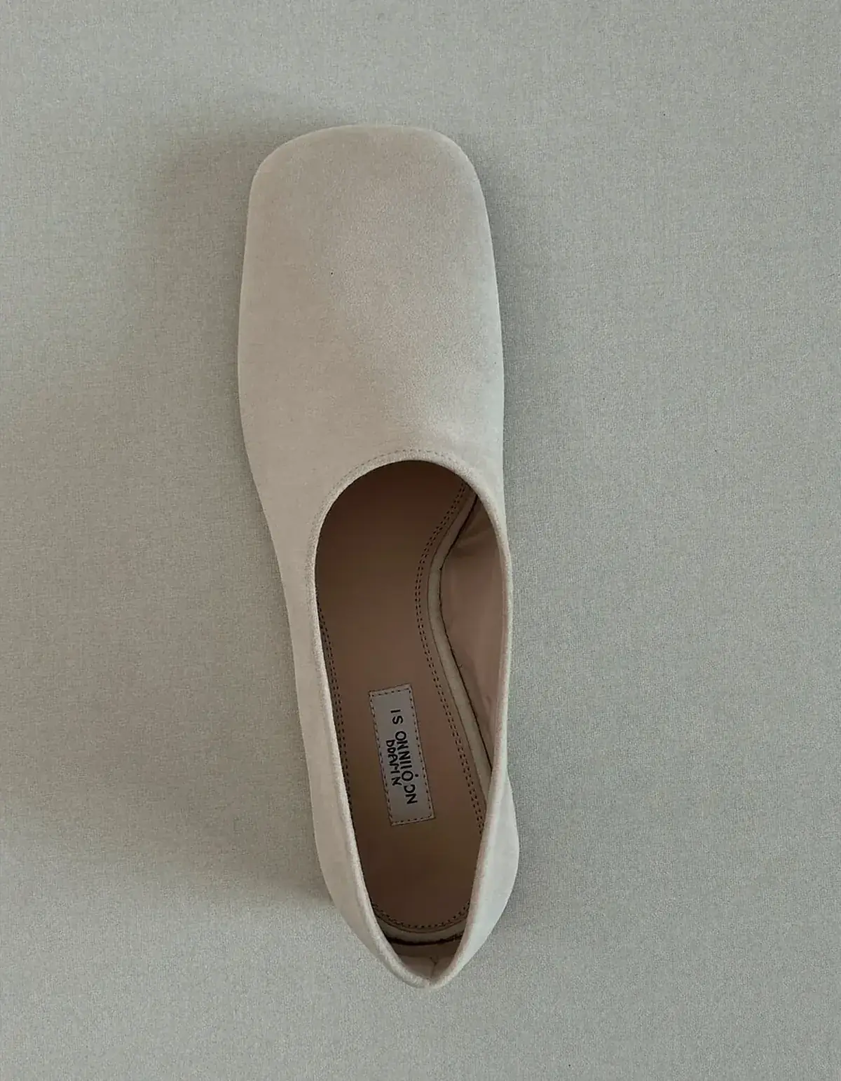 A single soft ivory leather loafer with a wide rounded toe box on pale oyster linen